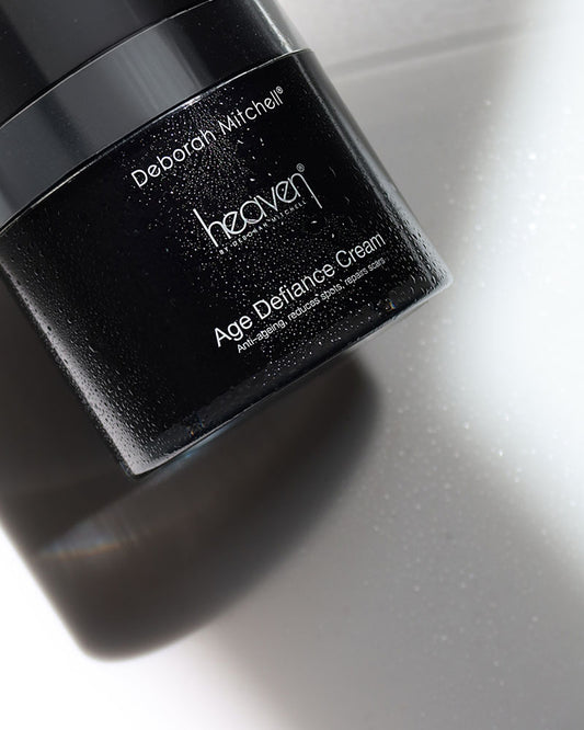 Black jar of Deborah Mitchell Heaven Age Defiance Cream on a reflective surface