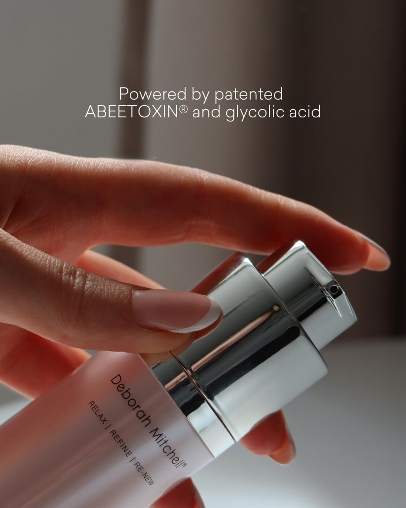 Two skincare bottles held by a hand with a blurred background