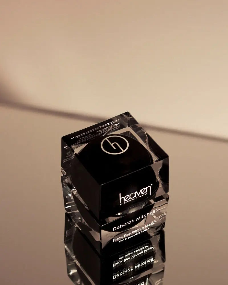 Stack of black cosmetic jars with 'heaven' branding on a beige background
