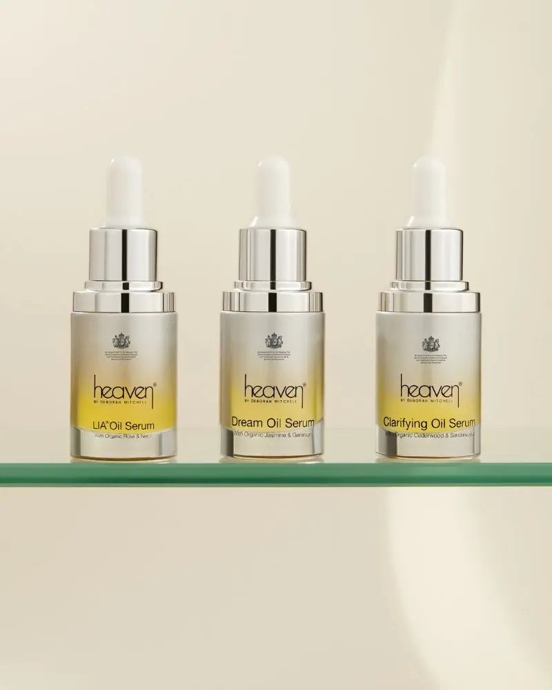Three bottles of 'heaven' oil serums on a glass shelf with a beige background
