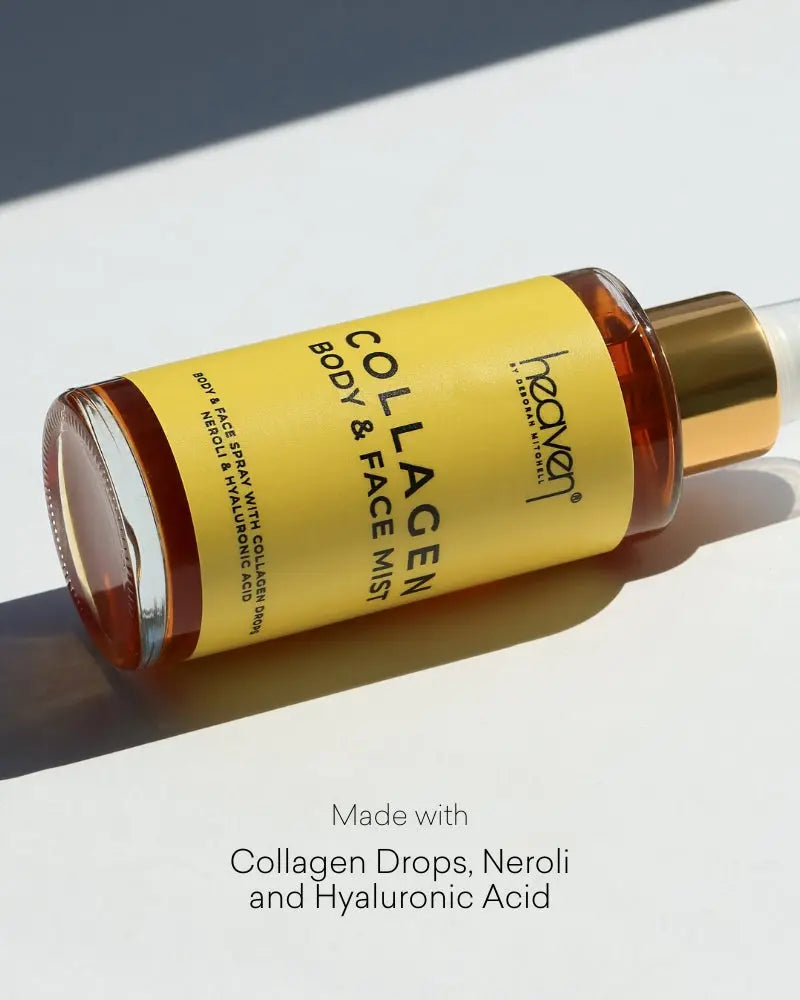 Bottle of heaven Collagen Body & Face Mist on a white background. Bottle has a bright yellow colour and the product itself is a rich golden tone. The product lies flat on a white background.