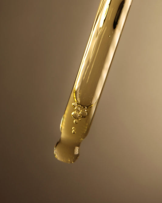 Gold-colored tool with a droplet of liquid on a gradient background