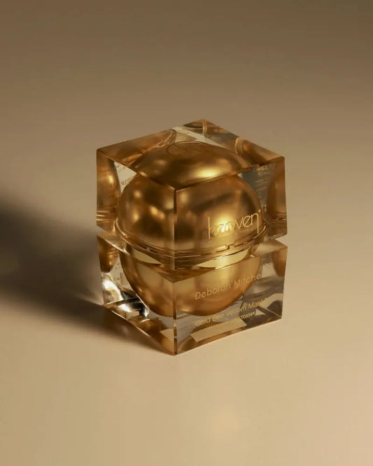 Gold cream jar with a clear cube lid on a beige background