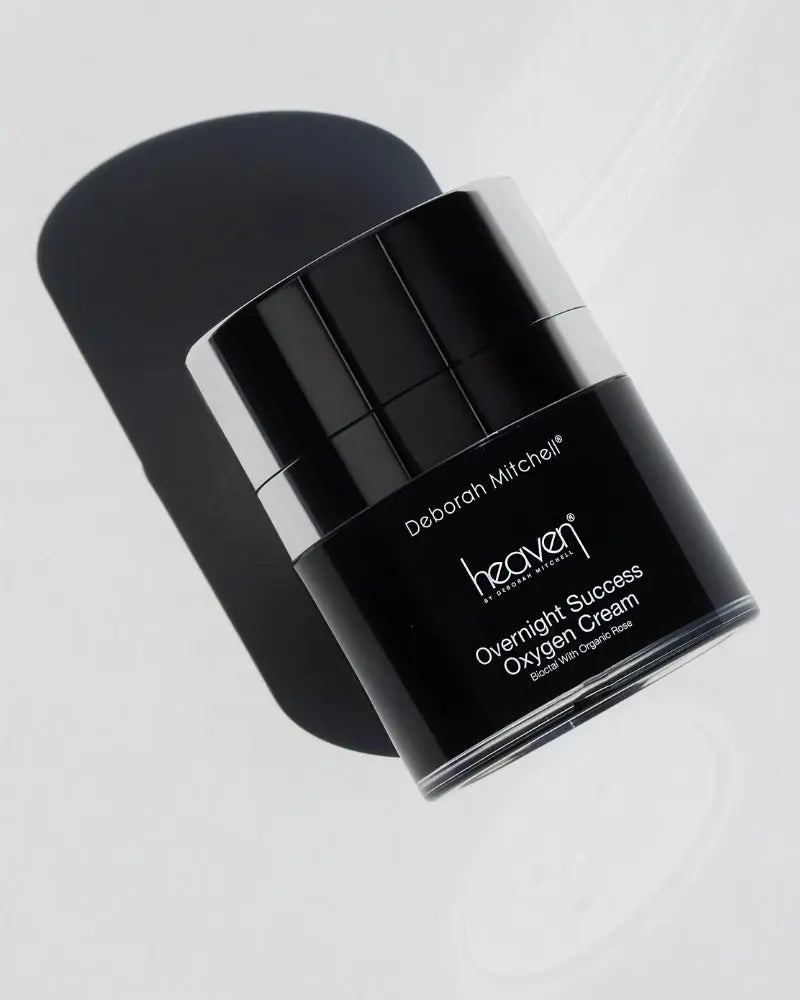 Black cream jar with silver cap labeled 'Deborah Mitchell Heaven Overnight Success Oxygen Cream' on a light gray background