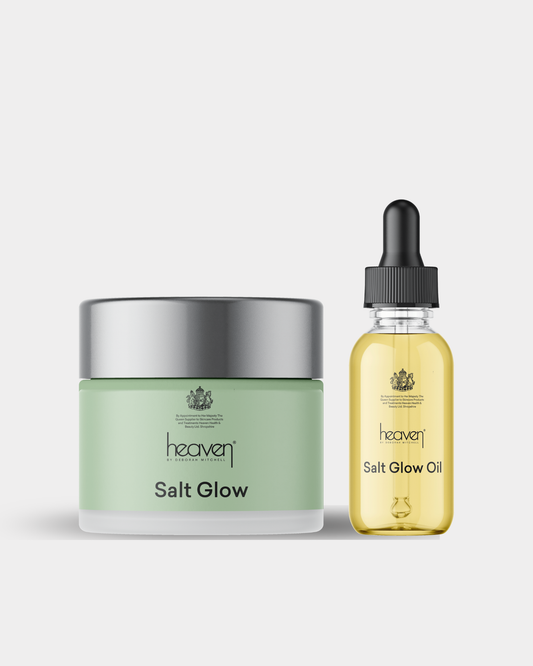 Green jar of salt glow scrub and yellow bottle of salt glow oil on a light gray background