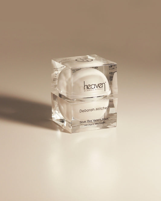 Skincare product in a clear container labeled 'heaven' by Deborah Mitchell on a beige background