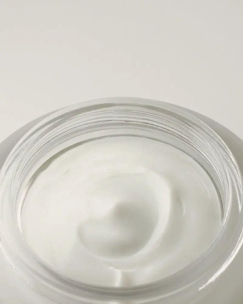 Close-up of a jar of white cream on a light gray background